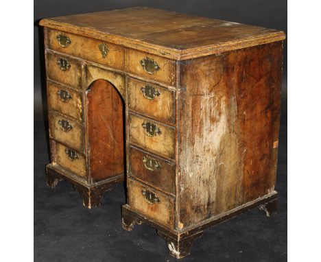 An early 18th Century walnut kneehole desk, the top feather-banded and with applied moulded edge above a single long drawer a