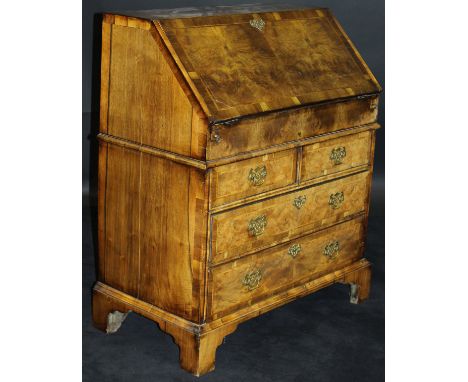 A 20th Century walnut bureau in the early 18th Century manner, the feather and cross-banded top above a sloping fall enclosin