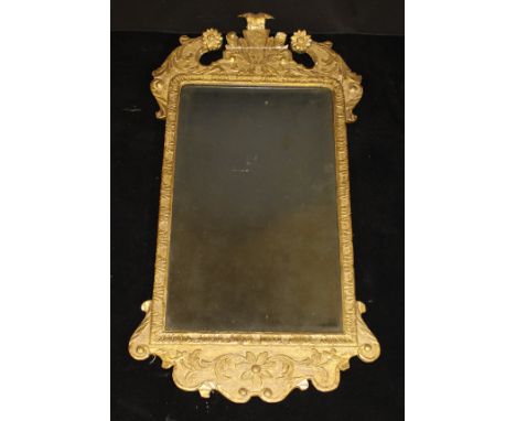 A George I giltwood and gesso framed wall mirror, the broken arch pediment with feathered scrolling foliate and flower head d