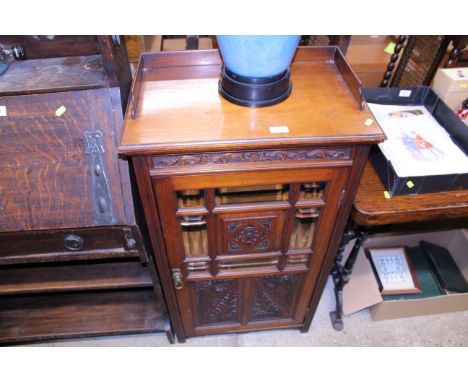 An Edwardian music cabinet with carved and bevelled glass door