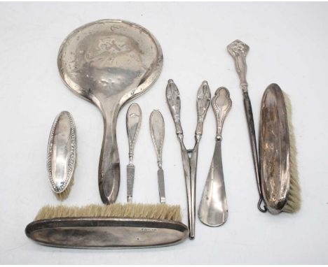 A George V silver backed hand mirror; together with a matching pair of silver backed clothes brushes; one other clothes brush
