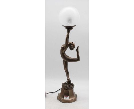 A reproduction Art Deco style table lamp, in the form of a female dancer holding a globular shade aloft in both hands, standi