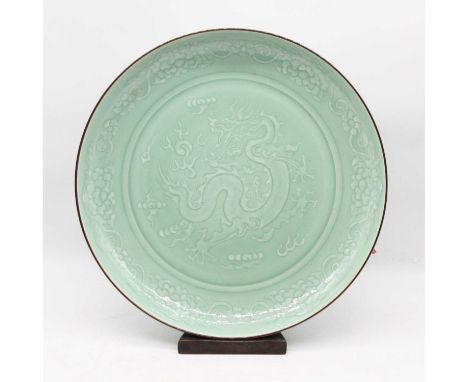 A Chinese export celadon glazed charger, the centre decorated with a four-claw dragon chasing a flaming pearl, within further