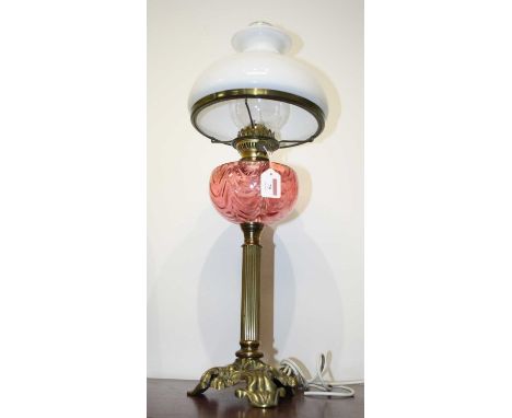 An early 20th century brass pedestal oil lamp, having an opalescent glass shade above a pink glass font, on a fluted column a