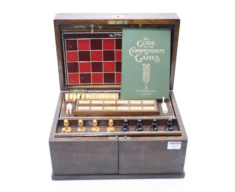 An Edwardian oak cased games compendium, the hinged lid opening to reveal a set of boxwood and ebony chess pieces, draughts p