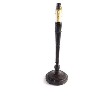 An early 20thC carved mahogany neoclassical candlestick, with metal fitting on tapering stem and circular foot, with a bead d