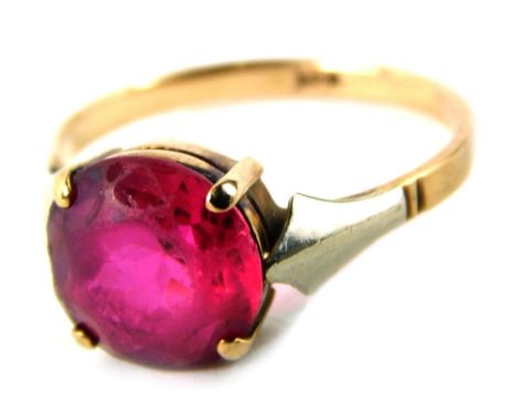 A 9ct gold garnet set dress ring, with single stone in four claw raised basket setting with bi colour shoulders, yellow metal