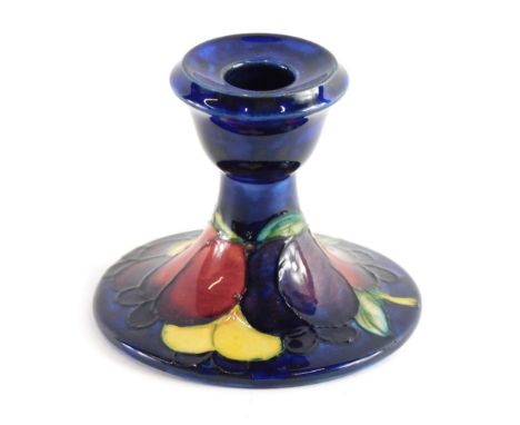 A Moorcroft Wisteria pattern candlestick, on blue ground, impressed and signature marks beneath, 9cm high.  