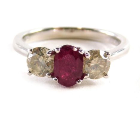  An 18ct white gold trilogy ring, set with an oval ruby approx. 1.10ct flanked by two round brilliant cut diamonds totalling 