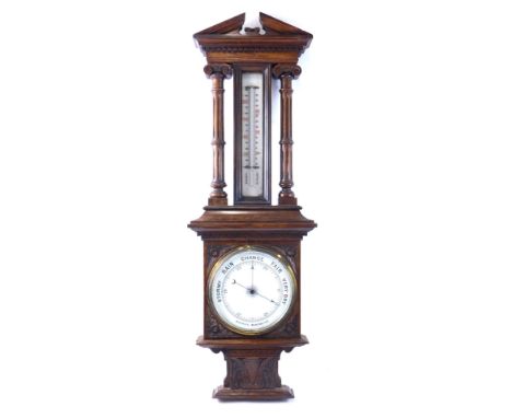 A late 19th/early 20thC aneroid barometer, in a carved oak case, decorated with leaves, fluted columns and a broken pediment,