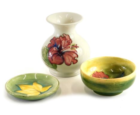 Various Moorcroft pottery, a vase, saucers and small bowl, various patterns, in light colours, impressed marks beneath, the v