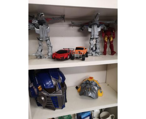 2 transformers toy masks together with shelf of toys. 