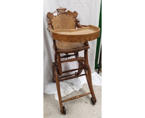 Victorian oak dolls high chair with cast roller feet. 