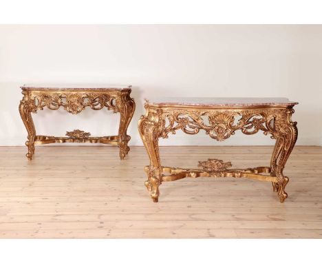 A pair of giltwood and rouge marble console tables,20th century, Continental, each with a shaped top above a carved apron, on