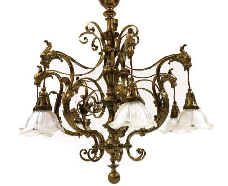 A large brass seven light electrolier,early 20th century, with seven moulded glass shades and lion mask scrolls surrounding a