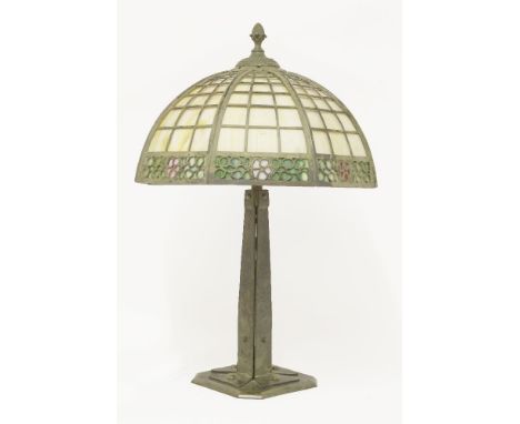 A Tiffany-style table lamp, an octagonal latticework shade with mottled yellow/white panels, over a band of flowers in pink a