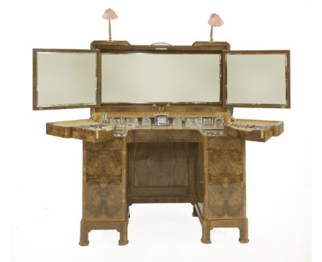 A walnut dressing table,with a truncated front, the hinged top opening to reveal a triptych mirror over a fitted dressing tab