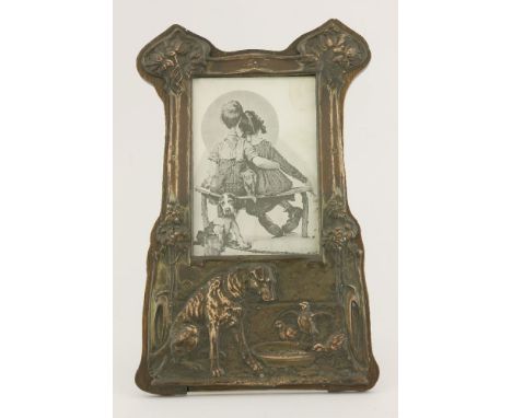 A copper photograph frame, embossed with a dog watching chicks drink out of his bowl, on an oak easel back,27.5cm high 13.5 x