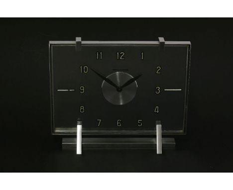 A Jaeger-LeCoultre chrome and glass table clock,with Arabic numerals, on triangular supports,21.5cm wide18cm high