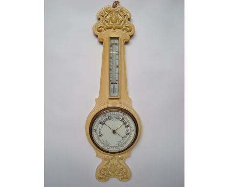 An early 20th Century later cream painted carved oak aneroid wheel  barometer with ceramic dial and thermometer. 