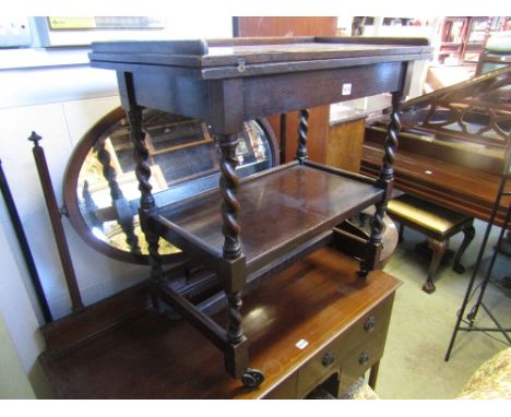 An Edwardian oak fold over top card table of rectangular form raised on barley twist supports