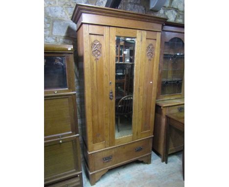 An Edwardian stripped oak single wardrobe with moulded cornice over a central three quarter length bevel edged mirror panelle