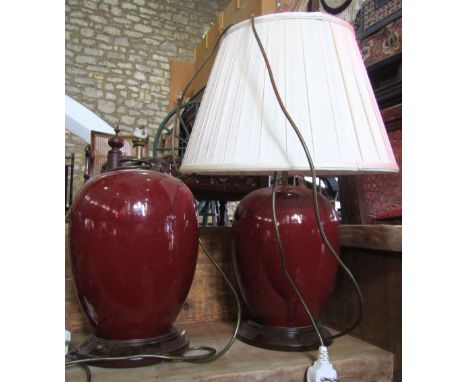 A pair of contemporary Chinese style oviform ceramic table lamps with ox blood coloured glazed, complete with pleated shades