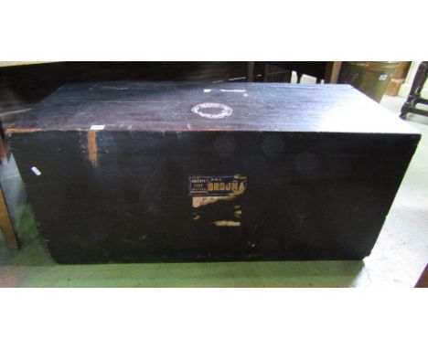 A vintage stained pine trunk with hinged lid, cast iron work side carrying handles and applied travel labels, together with o