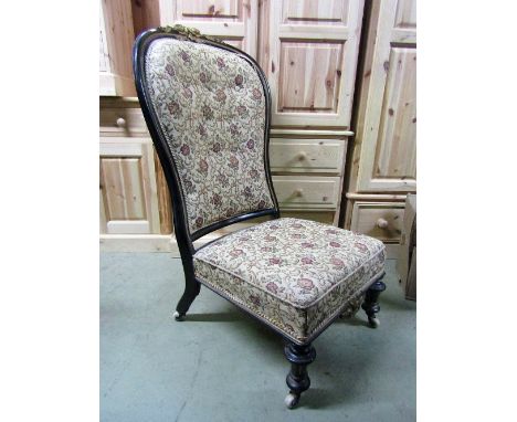 A Victorian nursing chair with upholstered seat and button back within an ebonised frame with shaped and moulded outline and 