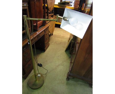 A vintage brass floor standing desk lamp with adjustable framework raised on a disc base