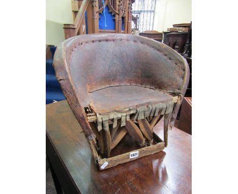 A primitive child's chair of continental origin with simple stick frame overlaid with hide and with scratched carved detail s