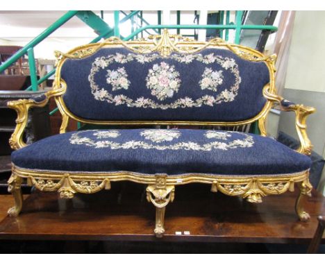 A substantial decorative continental gilt framed sofa, the flamboyant frame with ribboned, garland and swag and other detail,