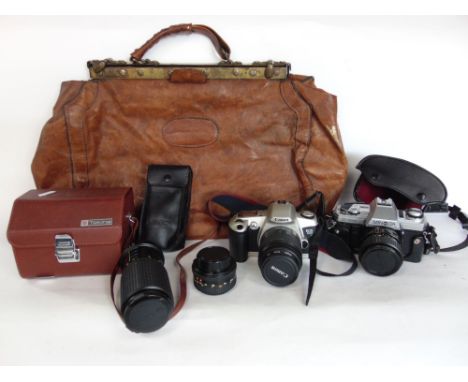 A collection of vintage cameras to include a Canon, a Minolta and various lenses; together with a vintage leather bag 