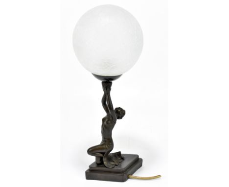 An Art Deco style bronzed figural table lamp with associated frosted glass shade, modelled as a semi-nude maiden kneeling sup