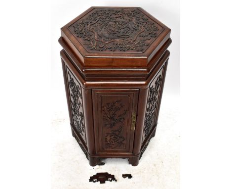 A Chinese carved hardwood hexagonal cupboard with removable top, decorated with phoenix and symbols, above a cupboard door, o