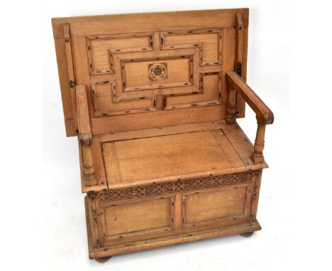 An early 20th century carved oak monk's bench with carved and panelled detail to the back above lift-up seat, width 90.5cm, d