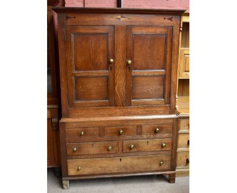 A George III North Wales oak cupboard, with two panelled cupboard doors above two dummy and two real long drawers, on bracket