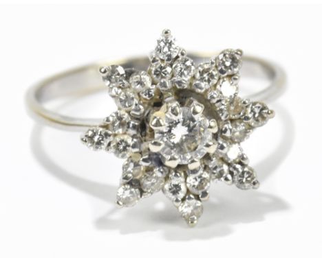 A 14ct white gold floral dress ring set with a central diamond approx .20ct, flanked by a melee of diamonds, approx size N.Ad