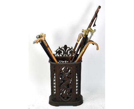A reproduction cast iron stick stand with cast floral detail, height 72cm, and a collection of assorted modern walking sticks