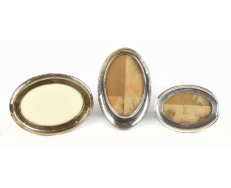 A George V hallmarked silver oval photograph frame with hinged wooden back, Birmingham 1910, height 18cm and two other hallma