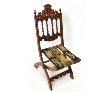 A Victorian carved walnut folding steamer type chair, the cresting rail carved with two dolphins and a crown above a needlewo