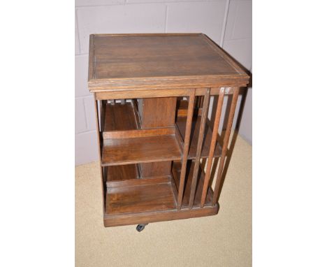 An early 20th Century oak revolving bookcase terminating in brass and ceramic castors, 80cms high.