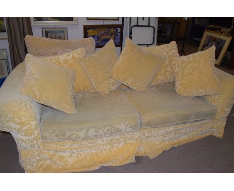 A sitting room suite comprising two three seaters; an armchair; and a pouffe, upholstered in gold coloured pattern material. 