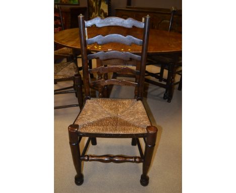 A set of four early 20th oak ladder back dining chairs with rush seats.