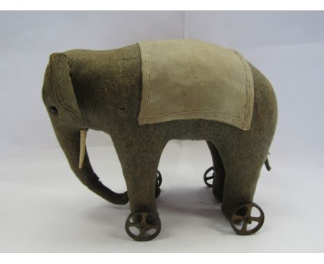 An early 20th Century Steiff straw filled felt pull along elephant with black boot button eyes on cast cast metal wheels, app