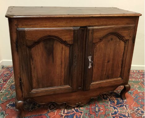 An 18th Century French oak buffet, the plain top with moulded edge above two arch panel cupboard doors enclosing a shelf rais