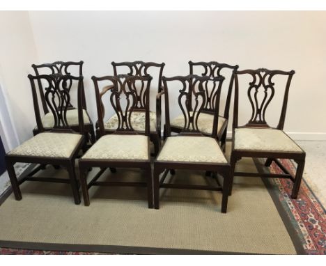 A set of seven mahogany framed Chippendale design dining chairs with carved and pierced back splat over a drop in seat on mou