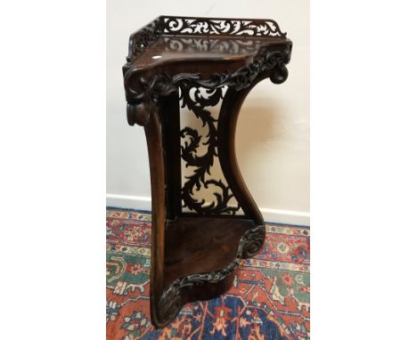 A Victorian rosewood corner shelf with fretwork galleried back over a serpentine front with applied scrolling foliate moulded