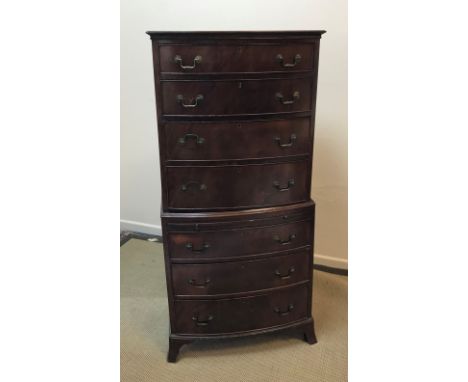 A reproduction mahogany bow fronted chest on chest, the upper section of four long graduated drawers with brass swan neck han