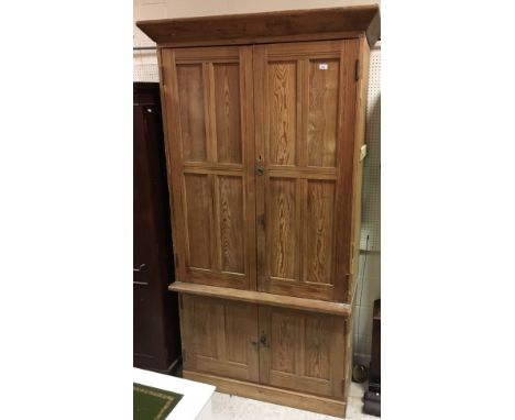 A Victorian pitch pine kitchen cupboard, the canted cornice over two four panelled cupboard doors enclosing four shelves, on 